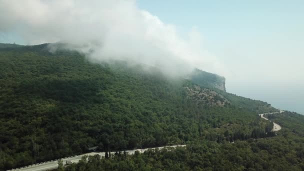 Krym s krásným výhledem na hory a dálniční silnicí mezi horami. Letecký pohled na rychlé zvlněné mraky plovoucí v horách a kopcích. — Stock video
