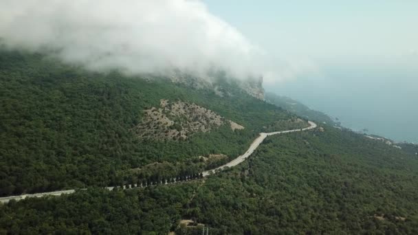 山々の美しい景色と山間の高速道路を持つクリミア。山や丘の上に漂う高速転がる雲の航空写真. — ストック動画