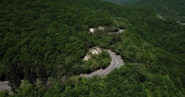 Dağ kıvrımlı zig zag yolu. Üst hava manzarası: Arabalar yukarıdan yola çıkıyor.