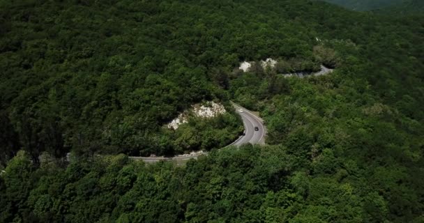 Bergkronkelende zigzagweg. Bovenaanzicht vanuit de lucht: auto 's die van bovenaf op de weg rijden. — Stockvideo