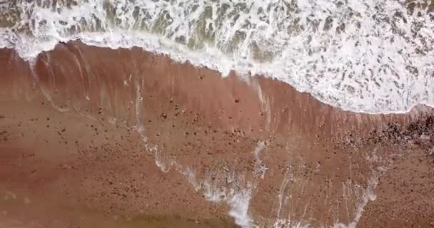 Vue du haut vers le bas des vagues se brisant dans le sable, survolant la plage de sable tropical et les vagues 
