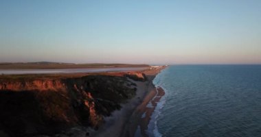 Güneş doğarken çekilmiş tropik plaj videosu, kıyı şeridine çarpan mavi köpüklü okyanus dalgalarının havadan kuş bakışı görüntüsü..