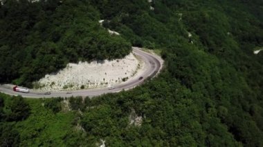 Virajlı yolun yukarısından Rusya 'da yeşil ormanlı dağda bir arabayla hava manzarası.