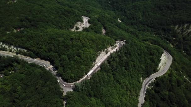 Вид сверху кривой дороги с автомобилем на гору с зеленым лесом в России — стоковое видео