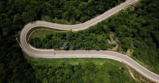 Letecký pohled z dronu zatáčky silnice s autem na hoře se zeleným lesem v Rusku — Stock video