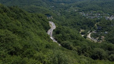 Virajlı yolun insansız hava aracı Rusya 'da yeşil ormanlı dağda bir arabayla görüldü.
