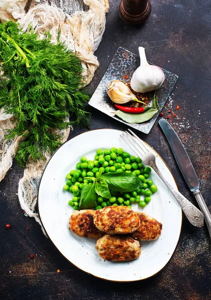 kızarmış tavuk pirzola beyaz plaka üzerinde yeşil bezelye ile 