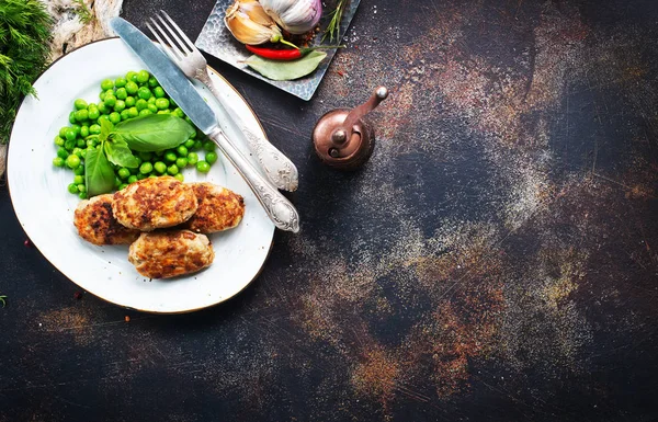 kızarmış tavuk pirzola beyaz plaka üzerinde yeşil bezelye ile 