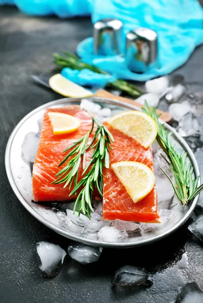 raw salmon slices with rosemary and lemon on ice