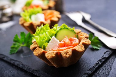 taze somon ve sebzeler üzerinde taş levha ile lezzetli tartlets 