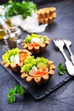 taze somon ve sebzeler üzerinde taş levha ile lezzetli tartlets 