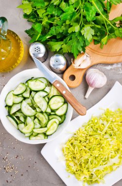 Vejetaryen salata, kıyılmış lahana ve mutfak masasında maydanoz ve sarımsak ile dilimlenmiş salatalık için malzemeler