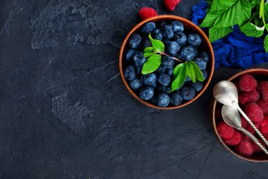 üstten görünüm taze yaban mersini ve ahududu ahşap kase masaya servis