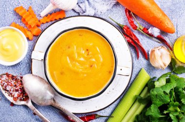 Havuç çorbası malzemeler tarafından çevrili kapta üstten görünüm