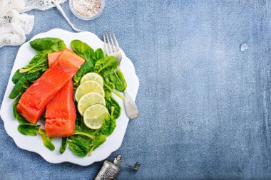 somon biftek kireç dilim ve taze ıspanak ile üstten görünüm plaka üzerinde