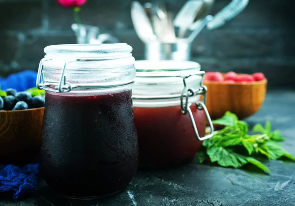 homemade jam in jars and fresh berries on background