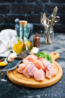 Ahşap tahta üzerinde mutfak eşyaları ile doğranmış çiğ tavuk fileto 