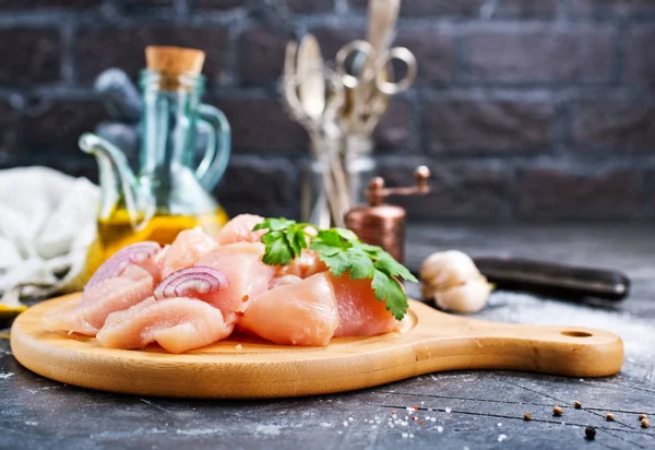 Ahşap tahta üzerinde mutfak gereçleri ile doğranmış çiğ tavuk fileto