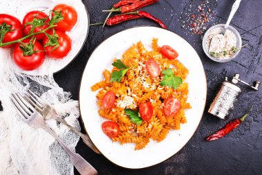 koyu arka plan üzerine domates sosu ve rendelenmiş peynir ile pişmiş makarna üstten görünüm