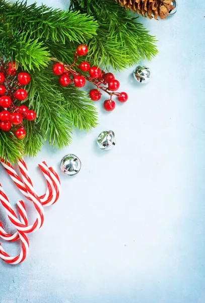 在蓝色桌面上与糖果藤条和冷杉树枝的圣诞节背景的顶部视图 — 图库照片
