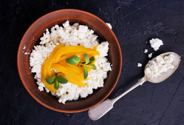 tatlı süzme peynir ve gri masa üzerinde bir kapta mango ile