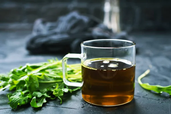 Fresh green arugula leaves and oil in glass cup on grey tabletop