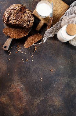 Ev yapımı çavdar ekmeği, ayçekirdeği ve eski masada bir şişe süt.