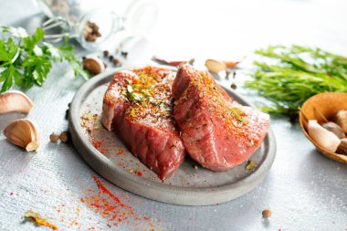 Çiğ et bifteği. Gri tabakta taze organik malzeme.