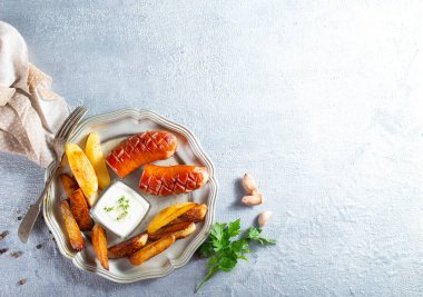 Kızarmış sosis ve metal tabakta patates.