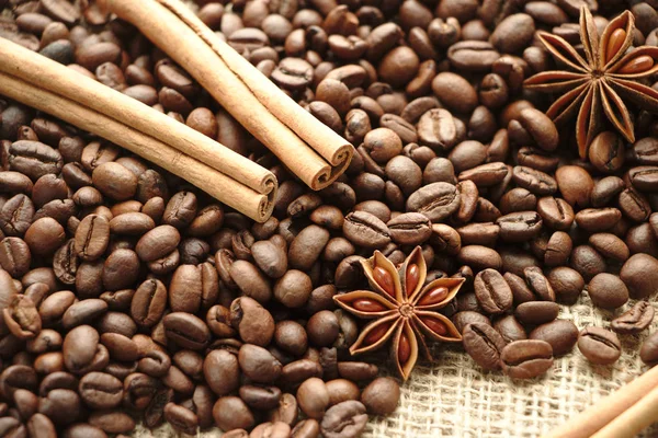 Roasted coffee beans on brown burlap background with spice as anise stars and cinnamon sticks. Hot brown colours.