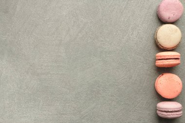 Tatlılar gri beton zemin üzerine. Farklı pastel renklerle macarons. Çerçeve ve renkli bir model tanımlama bilgilerini macarons Fransız. Sevgililer günü için hediye. Sevgililer günü arka plan