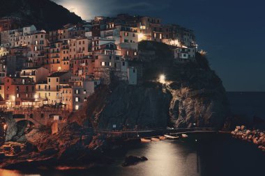 Manarola Akdeniz 'i ve Ay' ın yükselişini Cinque Terre 'deki uçurumdan gece vakti geçen binalarla gözden geçirir..
