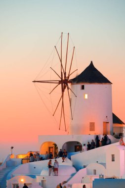 Santorini ufuk çizgisi Yunanistan 'da yel değirmeni ve binalarla birlikte gün batımı.