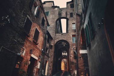 Siena, İtalya 'da eski binalar ve kemerli sokak manzarası.