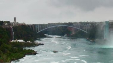 Niagara Falls, Kanada - 28 Eylül 2018: köprü ve American Falls - bulutlu gün Panning. Niagara Şelalesi dünyanın üç büyük şelaleler biridir.