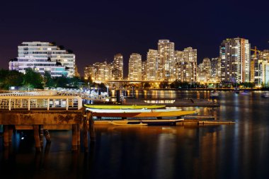 Vancouver şehri gece manzaralı binalar ve tekneler koyda.