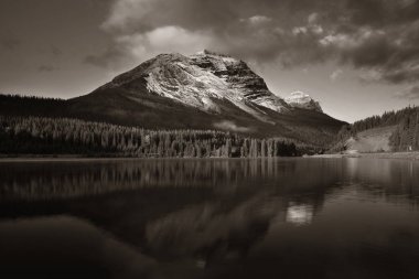 Kanada Banff Ulusal Parkı 'nda gün batımında yansımalı ve sisli dağ gölü.