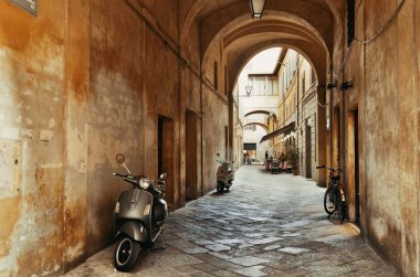 Siena, İtalya 'da eski binalar ve kemerli sokak manzarası.