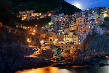 Manarola Akdeniz 'i ve Ay' ın yükselişini Cinque Terre 'deki uçurumdan gece vakti geçen binalarla gözden geçirir..