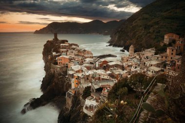 Vernazza 'da renkli bir gün batımı Cinque Terre, İtalya' da kayalar üzerinde binalar.