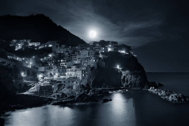 Manarola Akdeniz 'i ve Ay' ın yükselişini Cinque Terre 'deki uçurumdan gece vakti geçen binalarla gözden geçirir..
