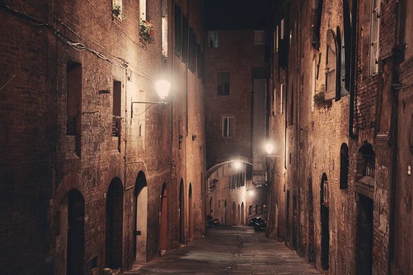 Street view with old buildings at night in Siena, Italy.