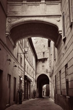 Siena, İtalya 'da eski binalar ve kemerli sokak manzarası.