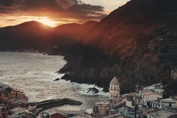 Vernazza 'da renkli bir gün batımı Cinque Terre, İtalya' da kayalar üzerinde binalar.