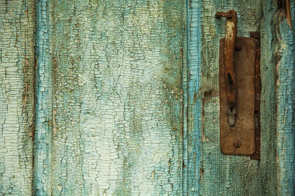 Old painted turquoise wooden door with peeling paint texture with metal lock (Fragment of ancient doors)