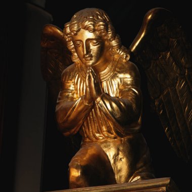 Koyu arka plan üzerinde dua eden bir melek figürü