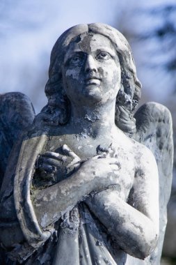 Mavi bir gökyüzü üzerinde dua eden bir melek figürü. Antik heykel.