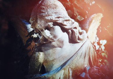 Antika karanlık yeşillik çerçevede bir güneş tarafından aydınlatılmış melek heykeli görkemli manzarası. Dramatik sahne. Retro filtre ve vintage tarzı. 