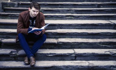 Genç adam yaşlı Europe şehirde kitap okumak