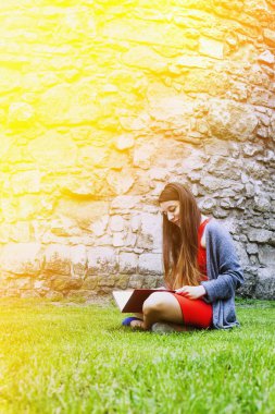 Kız öğrenci (eğitim, kendini geliştirme, kendi kendine organizasyon, zaman yönetimi parkta çim üzerinde öğrenme)